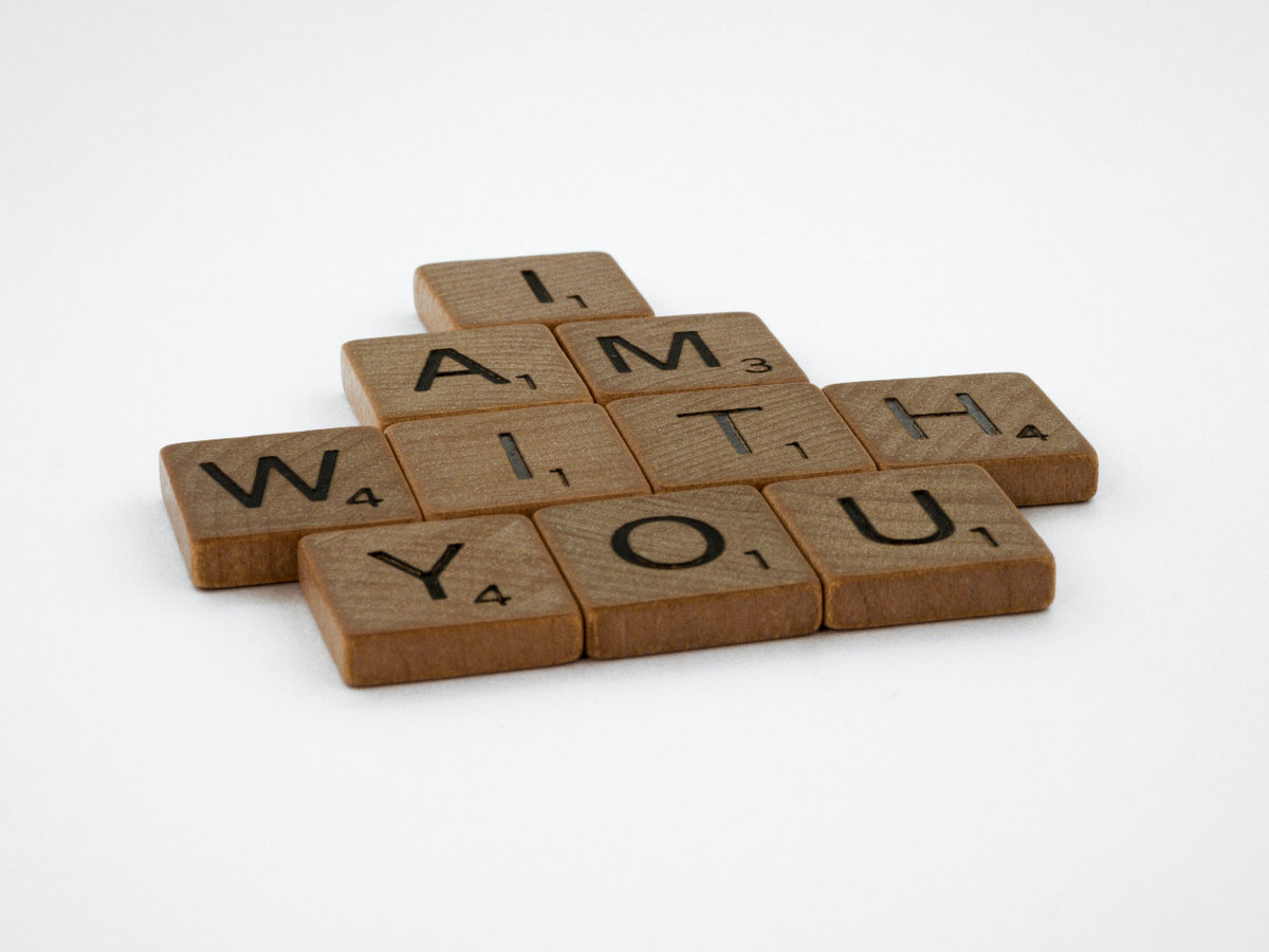 Scrabble tiles laid out on a white surface, spelling out  I Am With You