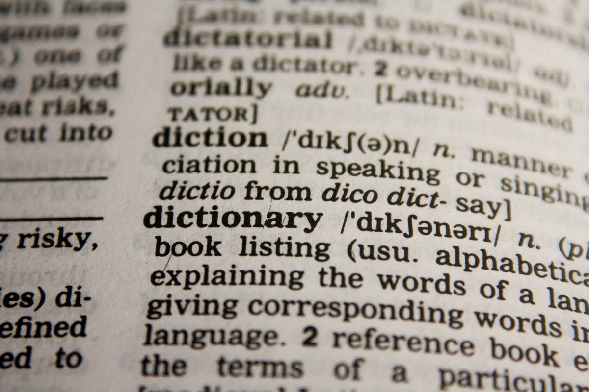 Image show close up of page in a Dictionary that defines the word 'dictionary'